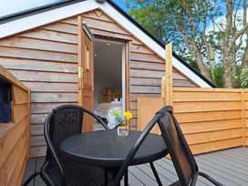 An outdoor deck with black table and chairs and a small vase with flowers outside a wooden building at The Halt in Maiden Newton