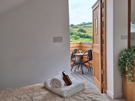 A bedroom with folded towels and a bottle on the bed facing an open door leading to a balcony with a table and two chairs at The Halt in Maiden Newton