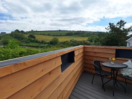 A wooden deck with a round table and two black chairs with a small flower vase on the table at The Halt in Maiden Newton