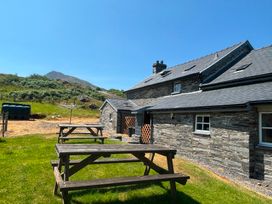 An outdoor area with benches and a cottage at Ty Siabod in Capel Curig near Betws-Y-Coed