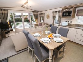 A dining table set with plates bowls and glasses next to a living area with sofas and a television at 117 Crosswinds Hillway near Bembridge