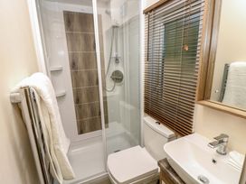 A bathroom with a shower enclosure towels a toilet a sink with a faucet a mirror and a window with blinds at 117 Crosswinds Hillway near Bembridge