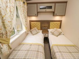 A bedroom with two single beds separated by a nightstand and cabinets above at 117 Crosswinds Hillway near Bembridge