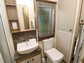 A bathroom with a sink a mirror a toilet a window with blinds and cabinets at 117 Crosswinds in Hillway near Bembridge
