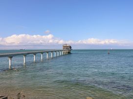A long pier extending over the sea with a building at the end and several ships in the water at 117 Crosswinds in Hillway near Bembridge
