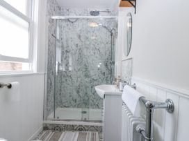 A bathroom with a shower, sink, and towel rack at 11A High Street, Jedburgh