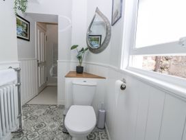 A bathroom with a toilet and mirror featuring a plant at 11A High Street in Jedburgh