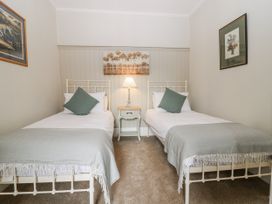 A bedroom with two single beds and a lamp at 11A High Street in Jedburgh