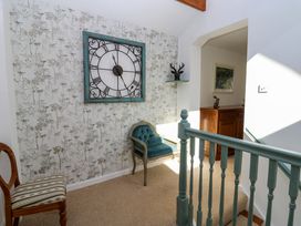 A hallway with a clock on the wall and a chair at The Museum in Nenthead