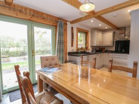 A kitchen and dining area with wooden table and chairs near glass doors with a view of trees at Bradan Lodge in Dalmally