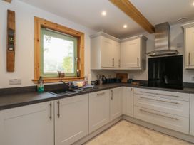 A kitchen with white cabinets gray countertops a window above the sink and a stainless steel range hood at Bradan Lodge in Dalmally
