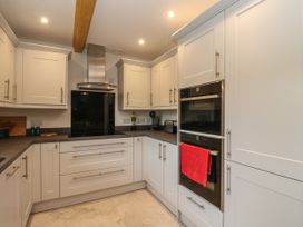 A kitchen with white cabinets black appliances and a red towel at Bradan Lodge in Dalmally