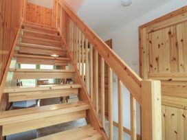 A wooden staircase with vertical railings next to a wooden door in a hallway at Bradan Lodge in Dalmally
