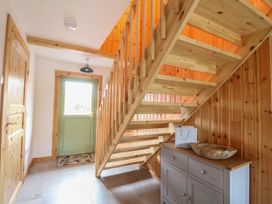 A wooden staircase in a hallway with a green door a gray cabinet and wood panel walls at Bradan Lodge in Dalmally