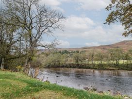 A river flowing through a landscape with trees on both sides and hills in the background at Bradan Lodge in Dalmally