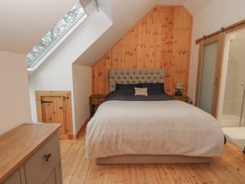 A bedroom with a bed against a wooden paneled wall skylight window and wooden furniture at Bradan Lodge in Dalmally