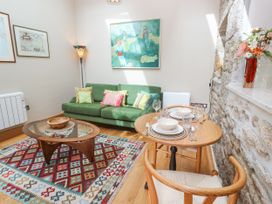 A living room with a green sofa and dining table at The Stables in St Just