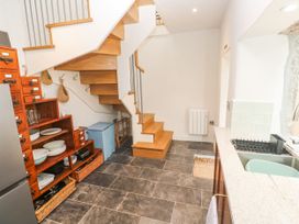 A kitchen with a staircase and wooden shelves at The Stables in St Just