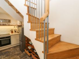 A staircase leading to an upper level with a view of kitchen appliances at The Stables in St Just
