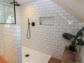 A shower with tiled walls and a wooden bench at Cotswold House in Moreton-In-Marsh
