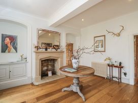 A living room with a fireplace and a table at Cotswold House in Moreton-In-Marsh