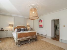 A bedroom with a bed, dresser, and lamp at Cotswold House in Moreton-In-Marsh