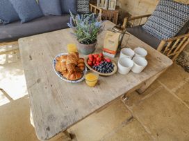 An outdoor seating area with a table set with croissants, fruits, and drinks at Cotswold House in Moreton-In-Marsh