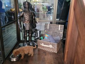 A dog near a food bowl with a knight statue and a wicker basket at St Edmunds Church in Fraisthorpe