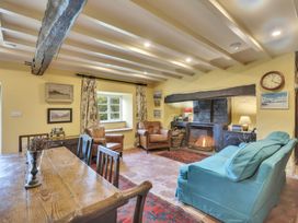A living room with a wooden dining table chairs a fireplace two armchairs and a sofa at Tan Y Clogwyn in Dolwyddelan near Betws-Y-Coed