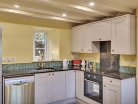 A kitchen with white cabinets a dishwasher an oven a sink a window and countertop appliances at Tan Y Clogwyn in Dolwyddelan near Betws-Y-Coed