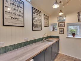 A kitchen with a wooden countertop and sink under framed posters and windows at Tan Y Clogwyn in Dolwyddelan near Betws-Y-Coed