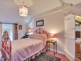 A bedroom with a double bed red metal frame side tables lamps a patterned rug and paintings at Tan Y Clogwyn Dolwyddelan near Betws-Y-Coed