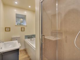 A bathroom with a sink, toilet, bathtub, shower enclosure, and a small window at Tan Y Clogwyn in Dolwyddelan near Betws-Y-Coed