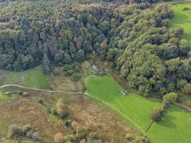 An aerial view of a clearing with buildings surrounded by trees and fields in Dolwyddelan near Betws Y Coed