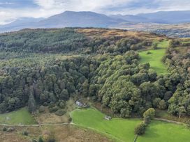 An aerial view of a rural landscape with dense forest patches green fields a few buildings and distant mountains at Tan Y Clogwyn in Dolwyddelan near Betws-Y-Coed