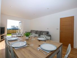 A dining room with a table set for dinner at 15 Llys Tegeirian Llangristiolus near Llangefni