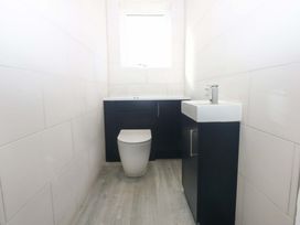 A bathroom featuring a toilet and sink with cabinetry at 15 Llys Tegeirian in Llangristiolus near Llangefni