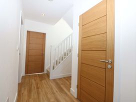 A hallway with doors and a staircase at 15 Llys Tegeirian in Llangristiolus near Llangefni