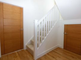 A hallway with a staircase and doors at 15 Llys Tegeirian Llangristiolus near Llangefni
