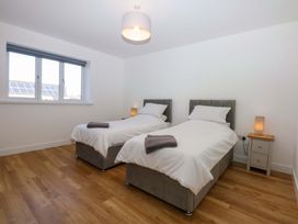 A bedroom with two single beds and a bedside table at 15 Llys Tegeirian Llangristiolus near Llangefni