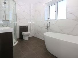 A bathroom with a shower, bathtub, and toilet at 15 Llys Tegeirian in Llangristiolus near Llangefni