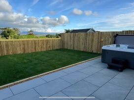 A garden with a hot tub and paved area at 15 Llys Tegeirian near Llangristiolus