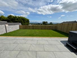 A garden with grass and a fence at 15 Llys Tegeirian in Llangristiolus near Llangefni