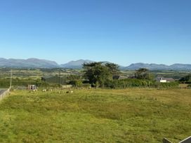 A view of fields and mountains at 15 Llys Tegeirian in Llangristiolus near Llangefni