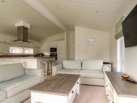 A living room with sofas coffee table and kitchen area with stools at Lakeview Lodge Forton near Garstang
