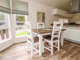 A dining area with a wooden table and four chairs in front of windows with blinds at Lakeview Lodge in Forton near Garstang