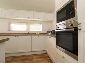 A kitchen with white cabinets a stainless steel oven and microwave wooden countertops and a window with blinds at Lakeview Lodge in Forton near Garstang