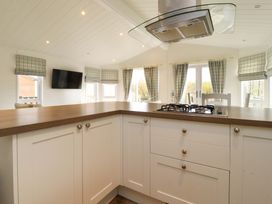 A kitchen with white cupboards a wooden countertop and a gas stove under a stainless steel vent hood at Lakeview Lodge in Forton near Garstang