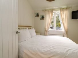 A bedroom with a white bed near a window with curtains and paintings on the wall at Lakeview Lodge in Forton near Garstang