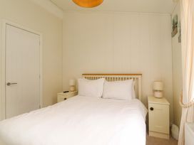 A bedroom with a double bed white bedding two side tables with lamps and a closed door at Lakeview Lodge in Forton near Garstang